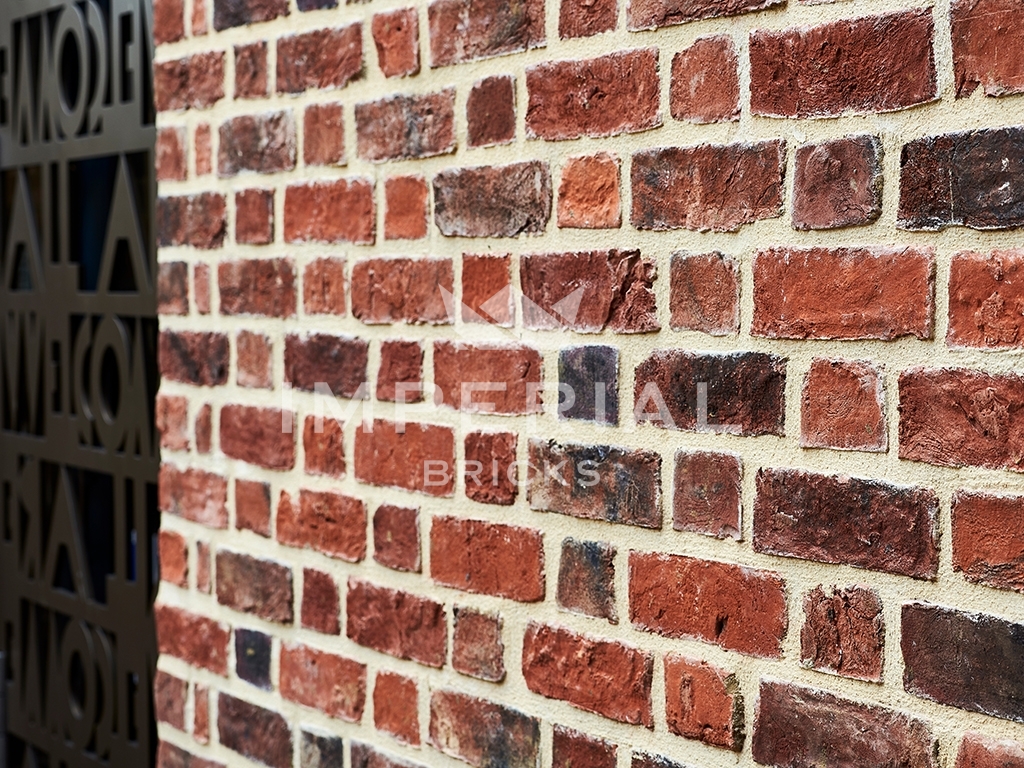 Close up angle view of wall of a church extension, built using a bespoke blend of handmade bricks and burnt headers.