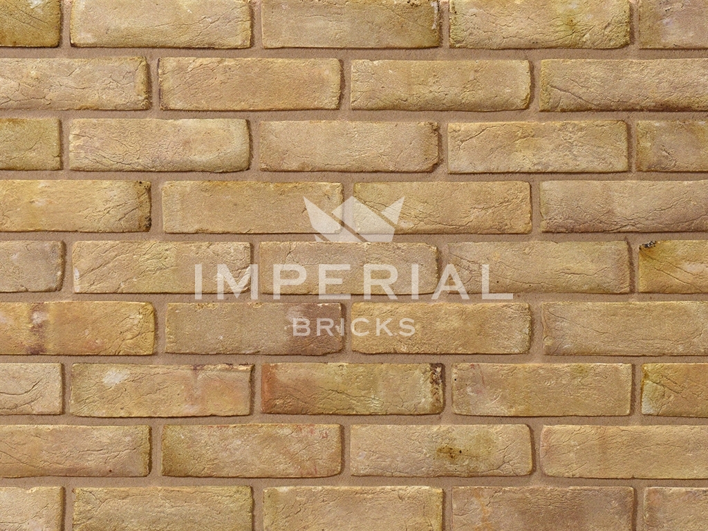 Cambridge Buff bricks shown in a wall. The bricks are creamy yellow and have subtle pink tones, with creasing on the faces.