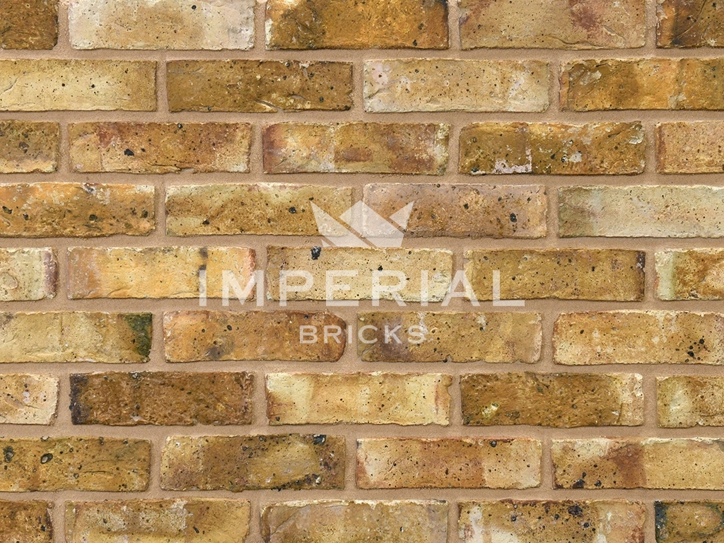 Original London Stock handmade bricks shown in a wall. The bricks are yellow and have coal spotting on the faces.