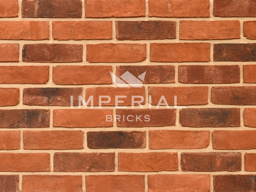 Country Blend handmade bricks shown in a wall. The bricks are mostly orange shades blended with soft browns and reds, with a creased texture.