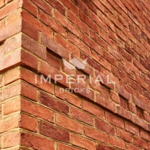 Corner of a residential self-build home, built using Farmhouse Orange handmade bricks. Image is taken close up to show the detail and texture in the brickwork.