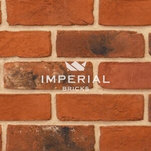 Imperial Blend handmade bricks shown in a wall. The bricks are mixed red and orange shades blended with darker weathered and subtly mortared bricks. Zoomed in to show detail and texture.