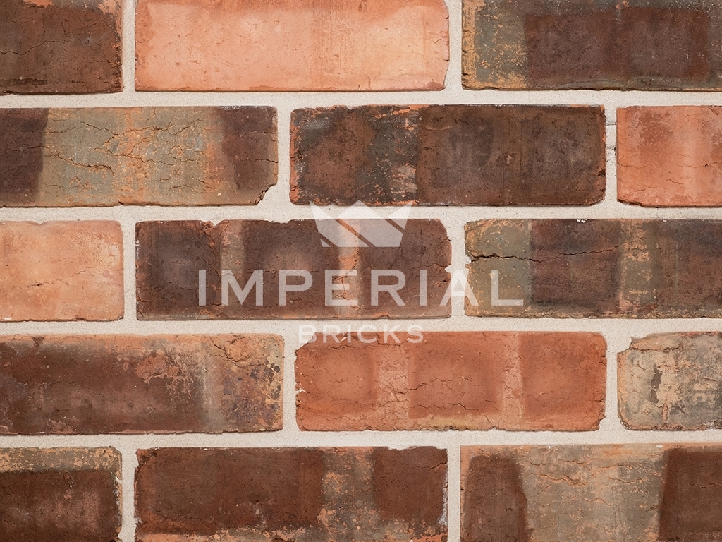 Victorian Pressed Brick Tiles shown on a wall. The tiles are a red base colour with distinctive pale banding and tonal weathering.