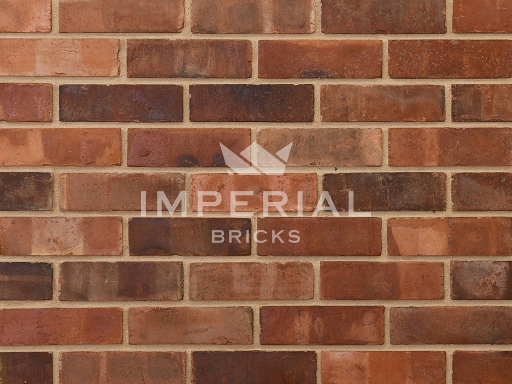 Weathered Outside Blend bricks shown in a wall. The bricks are red to orange colour, with pale banding, dark overburns and tonal weathering.