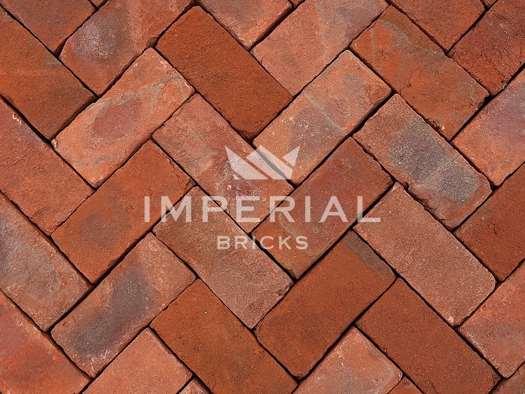 Hampton Blend handmade pavers laid in the ground. The pavers are a blend of red and orange with subtle weathering on the faces and a sandy creased texture.