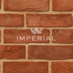 Imperial Orange Stock handmade bricks shown in a wall. The bricks are a soft orange colour with some multi shades, have subtle creasing on the faces and neat square edges. Zoomed in to show detail and texture.